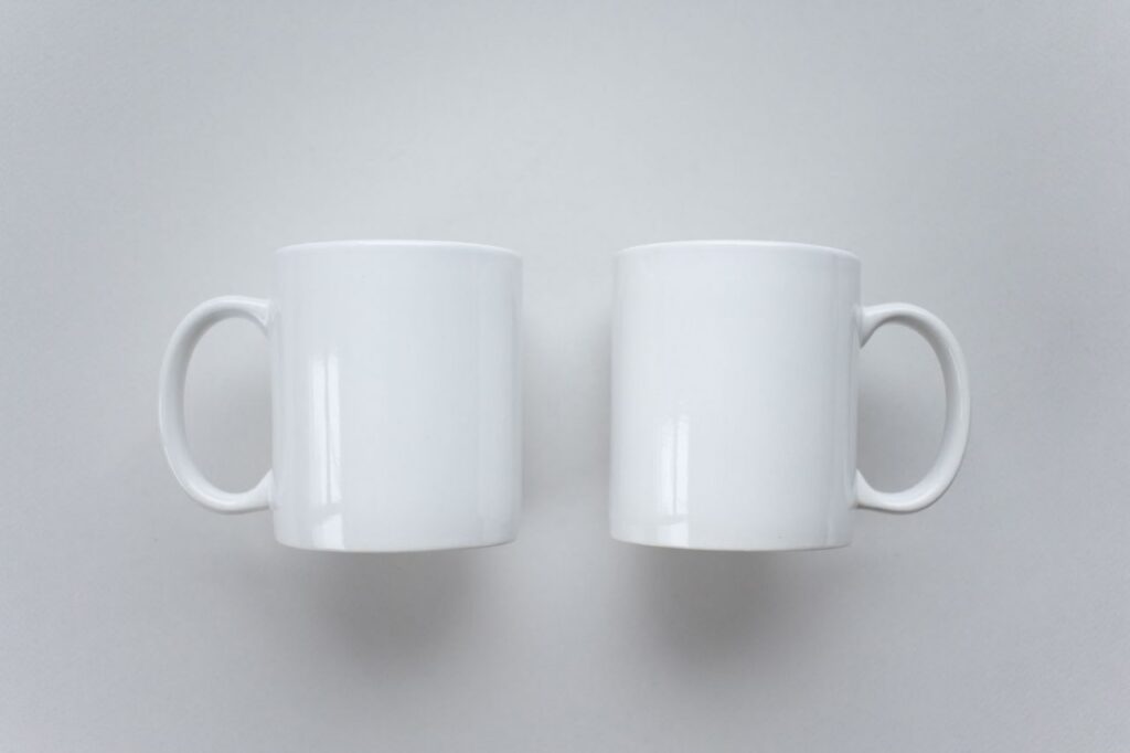 Simple white coffee mugs on a flat surface, perfect for mockup designs.
