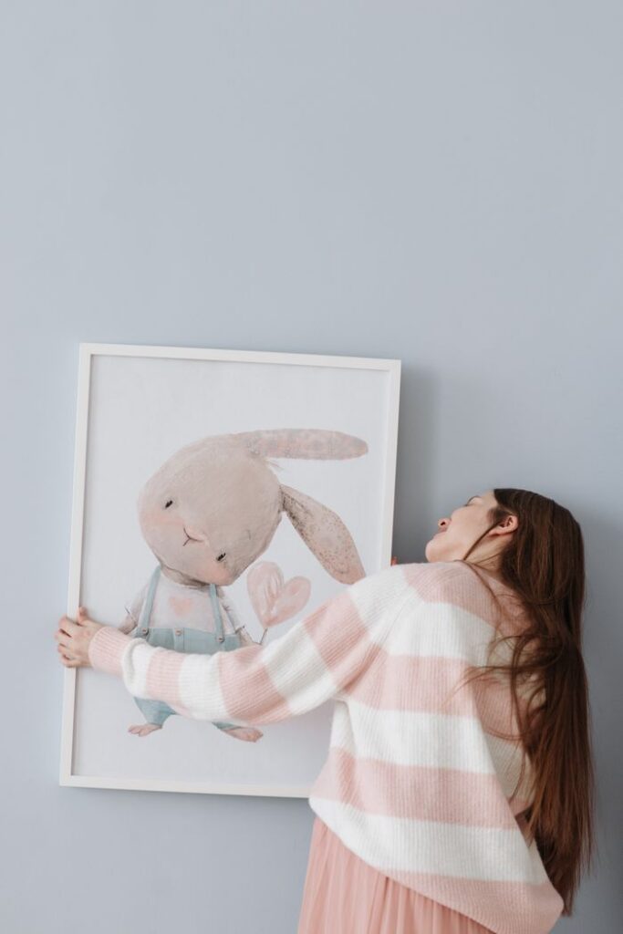 A woman decorates a room with an adorable bunny-themed picture frame.