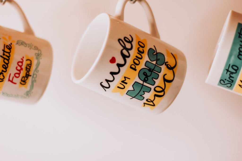 Colorful mugs with inspirational words in Portuguese displayed creatively.